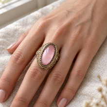 Load image into Gallery viewer, Vintage 875 silver gilt pink amethyst cabochon ring worn on a finger, showing its oval shape and intricate filigree frame.