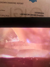 Load image into Gallery viewer, A close-up of a laboratory-grown diamond with a visible engraved lot number, shown against a background containing a diamond report card header.