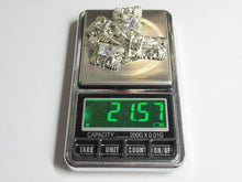 Load image into Gallery viewer, A pile of silver-toned ornate jewelry pieces, likely crystals or rhinestone settings, displayed on the weighing platform of a digital pocket scale with a green LCD display showing 21.57 grams.