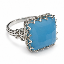 Load image into Gallery viewer, Side view of vintage sterling silver blue agate ring showing a raised cushion-shaped gemstone, intricate prong details, and decorative silver scrollwork.
