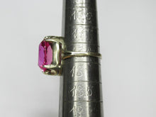 Load image into Gallery viewer, A pink gemstone ring set in a gold band, displayed on a silver ring sizer against a light gray background.
