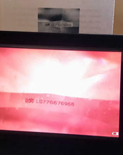 Load image into Gallery viewer, A close-up of a black electronic device, likely a barcode scanner or terminal, displaying a red and white screen with the barcode number LG776676968. A small paper label with the same barcode is visible behind the device.
