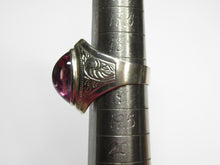 Load image into Gallery viewer, Side view of an 875 silver amethyst cabochon ring on a sizing mandrel, showing the engraved shoulder and raised bezel.
