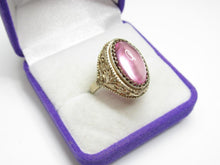 Load image into Gallery viewer, Angled view of an 875 silver gilt amethyst cabochon ring showing the scalloped bezel and open floral filigree shoulder.

