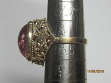 Load image into Gallery viewer, Side view of an 875 silver gilt amethyst cabochon ring on a sizing mandrel, showing the raised stone and filigree shoulder.
