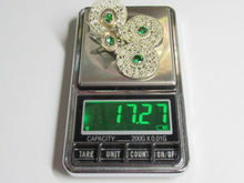Load image into Gallery viewer, A pair of silver-toned statement earrings with round green gemstones and clear crystals, displayed on a digital scale showing a weight of 17.27 grams.
